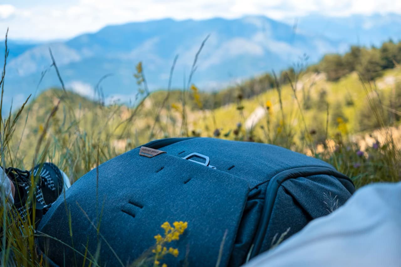 Fotografía contextual de una mochila Peak Design en un prado de montaña, aportada desde Unsplash.